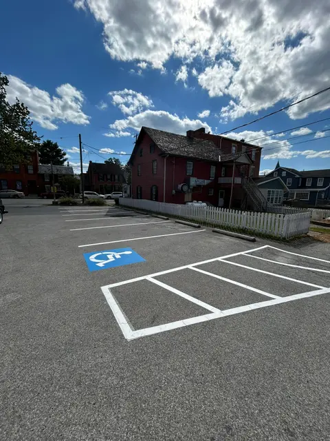 ADA parking stall with white outline and access aisle hatching beside a historic building