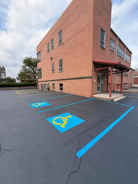 Blue ADA stall with the symbol of access and blue lines beside a brick building