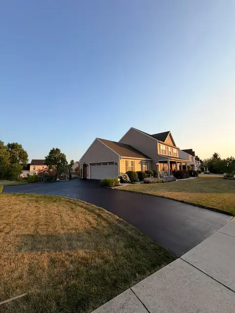 Curved driveway sealcoated at dusk in a residential neighborhood