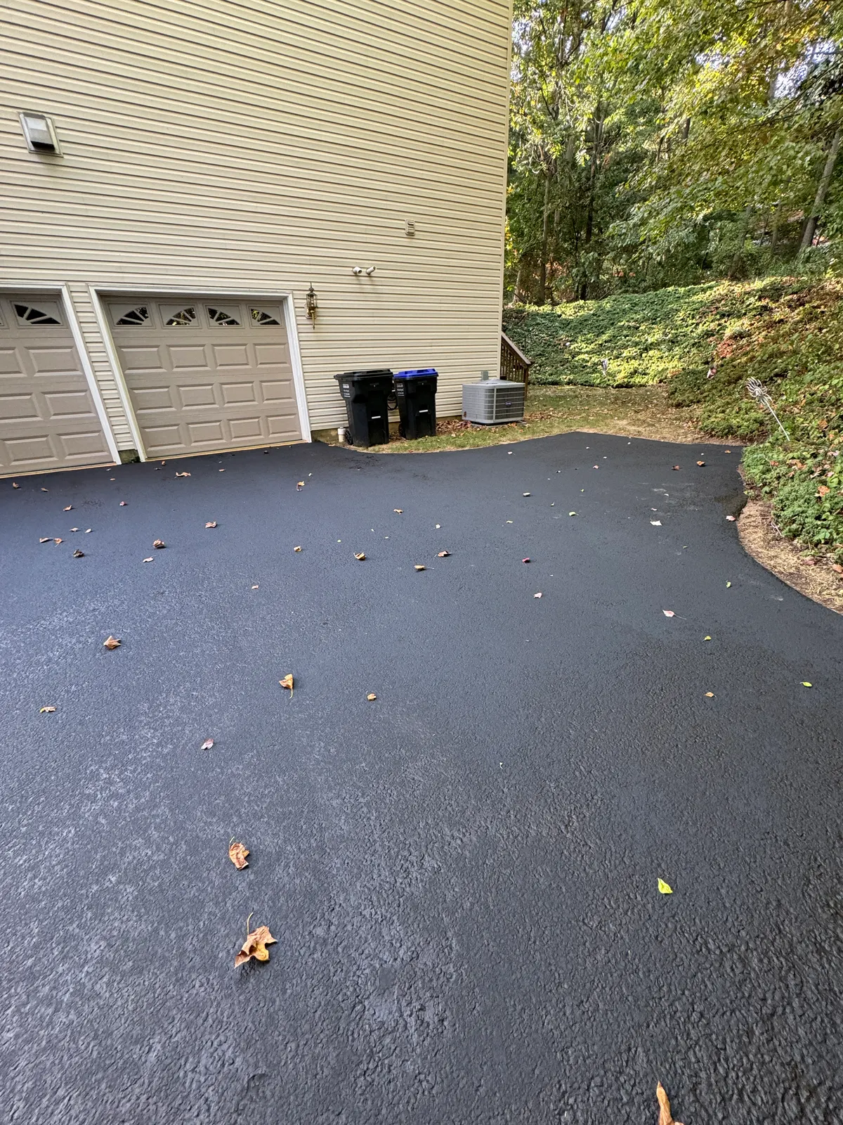 Freshly finished asphalt pad in front of a double garage