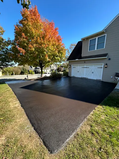 Sharp black sealcoat in front of a garage on an autumn day