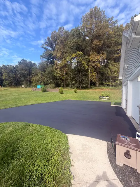 Sealcoated driveway with a clean edge along a concrete walkway