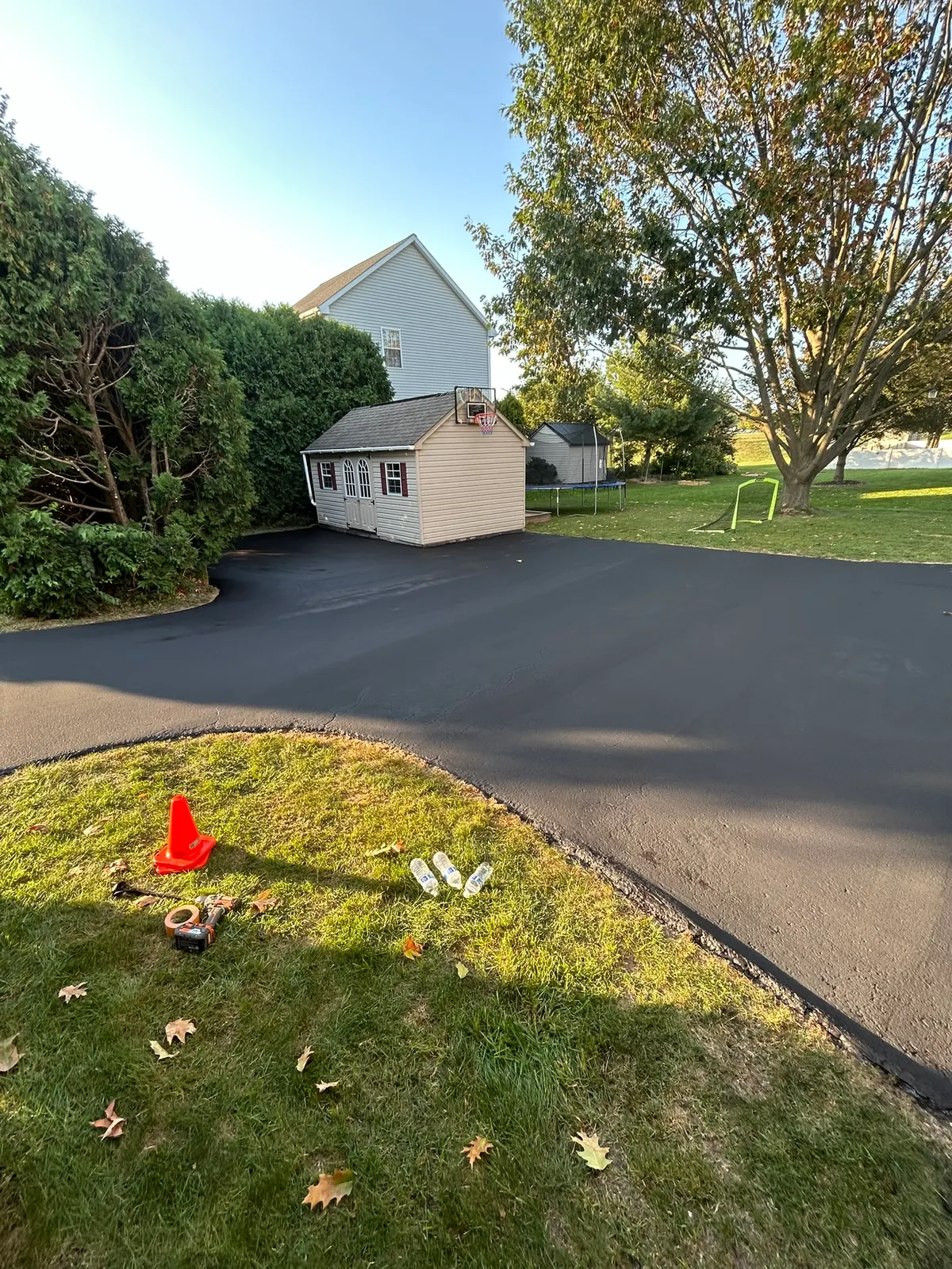 Newly sealcoated curved driveway beside a lawn and garden shed