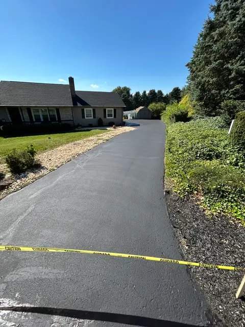 Long ranch house driveway with fresh sealcoat and caution tape