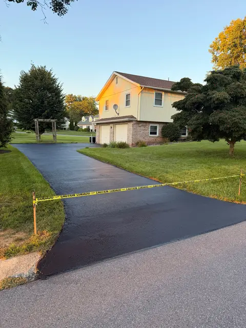 Sealcoated driveway taped off in front of a two-story home