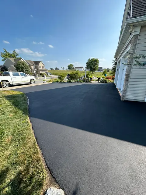 Wide sealcoated driveway apron in front of a two-car garage
