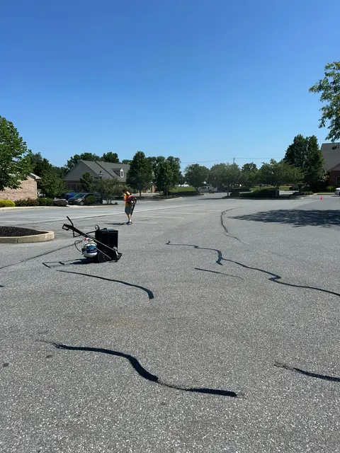 Crack sealing equipment and freshly filled cracks across a parking lot