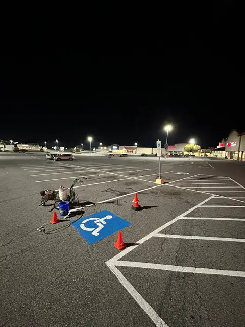 Night striping crew work on a blue ADA stall surrounded by cones