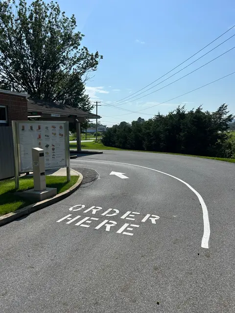 ORDER HERE stencil and curved arrow on a drive-through lane
