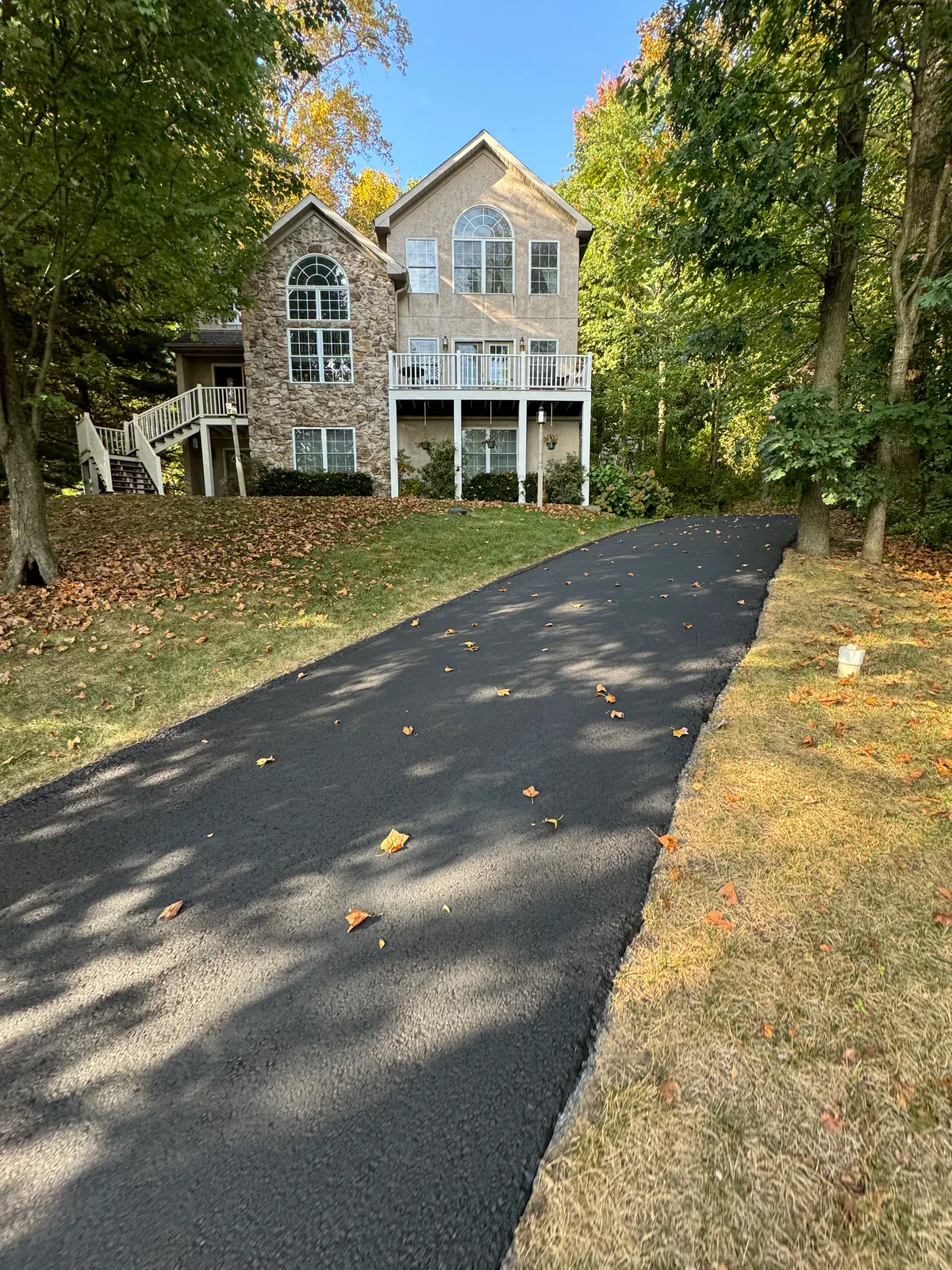 New asphalt driveway leading up to a large home