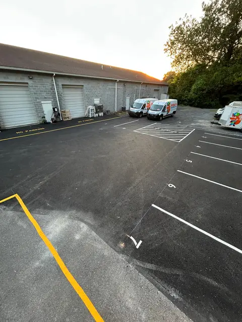 Rear lot with stall lines, stencils and a yellow curb line beside a building