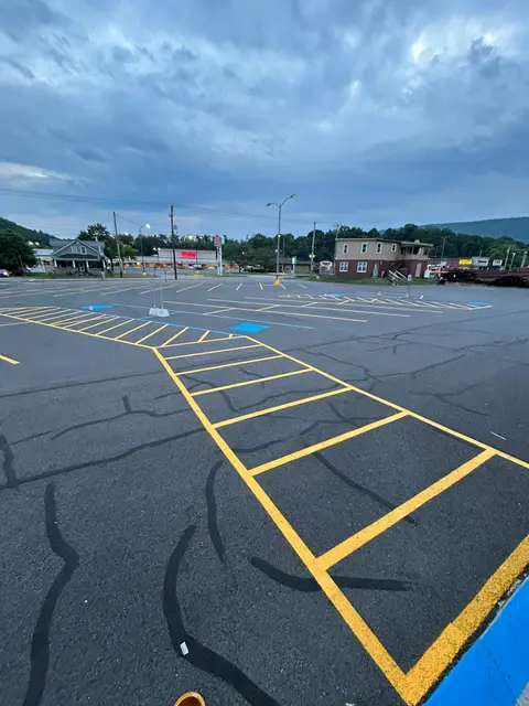 Angled yellow parking stripes laid out on a crack-filled asphalt lot