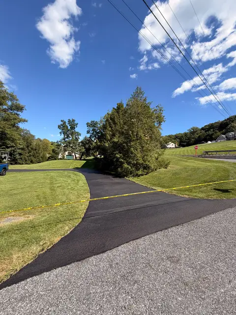 Rural driveway freshly sealed and taped off where it meets the road