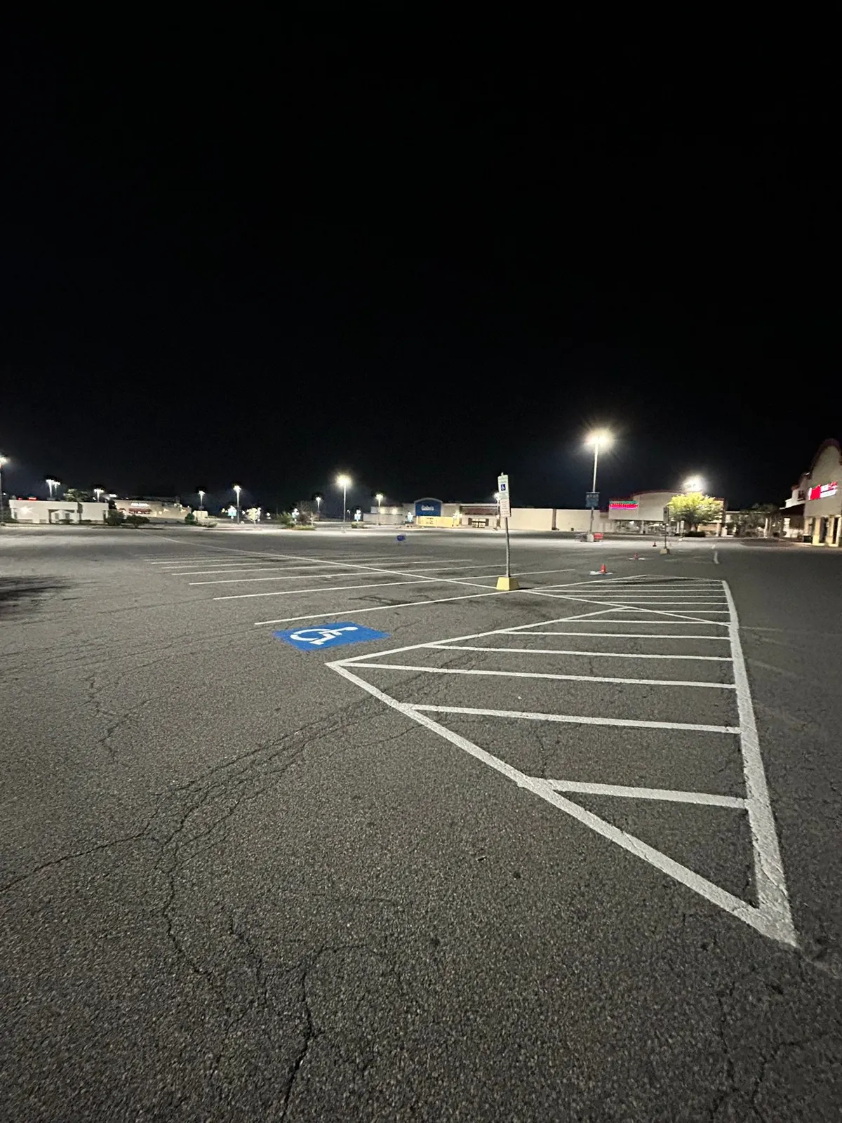 Hatched ADA access aisle in a shopping center lot at night