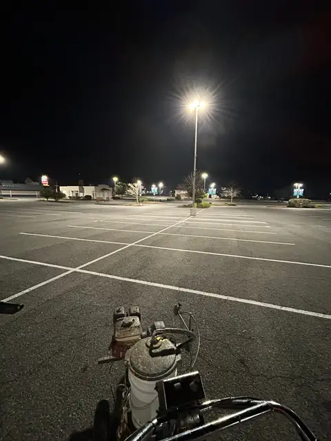 Line striping machine on a freshly marked commercial lot at night
