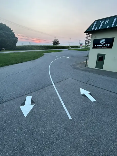 White directional arrows and a curved lane line painted on a business entrance drive