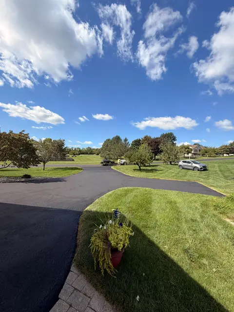 Wide driveway sealcoated past a planter and lawn